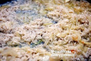 Выложить на обжаренный в масле лук, промытый и обсушенный рис