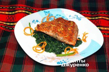 На велику тарілку викласти зелений соус зі шпинату, розподіливши його по всій тарілці. Поверх соусу викласти філе риби на грилі