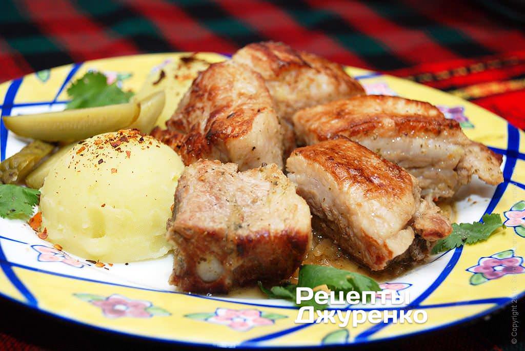 Готова страва Тушковані свинячі ребра в соусі — м'ясо з коріандром і зеленню