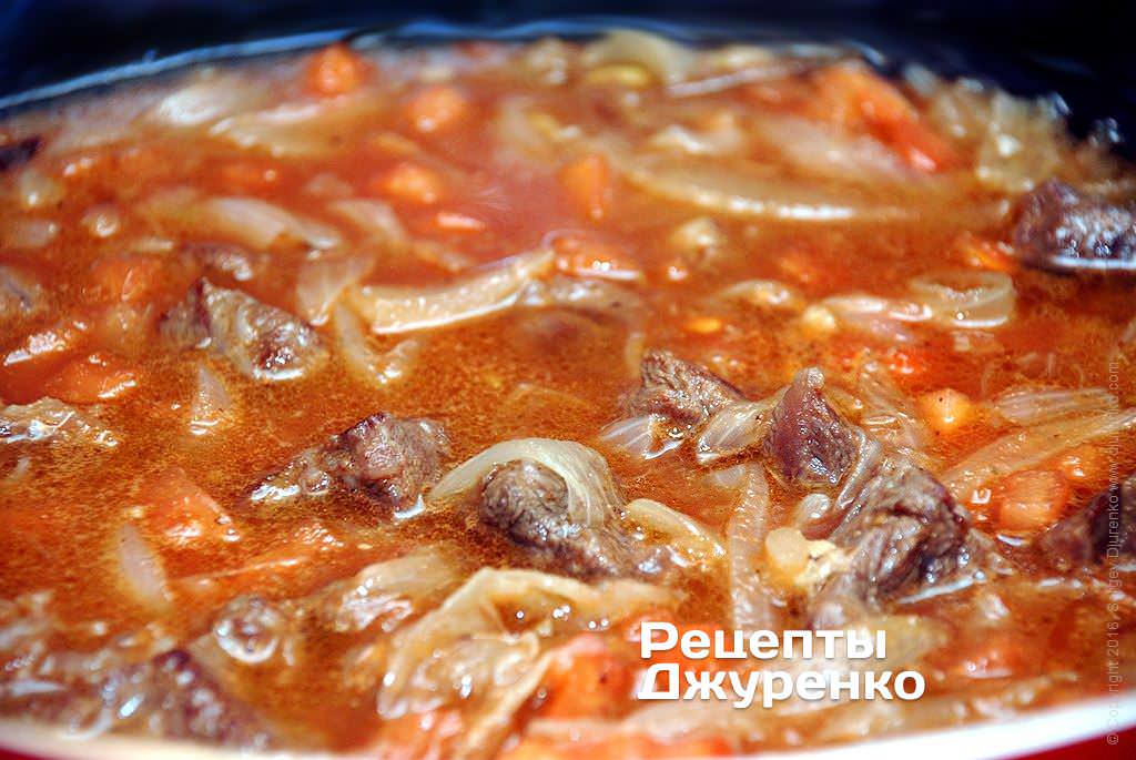 Тушить мясо с луком и томатом под крышкой.