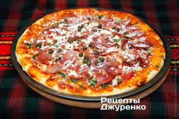 Разложить прошутто, каперсы и посыпать сыром.