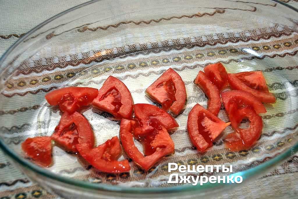 Смазать форму для запекания маслом и выложить немного нарезанного помидора.