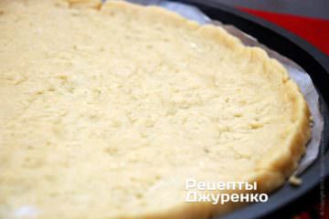Положите на бумагу больший кусок теста и сухими руками растягивайте тесто в тонкий слой.