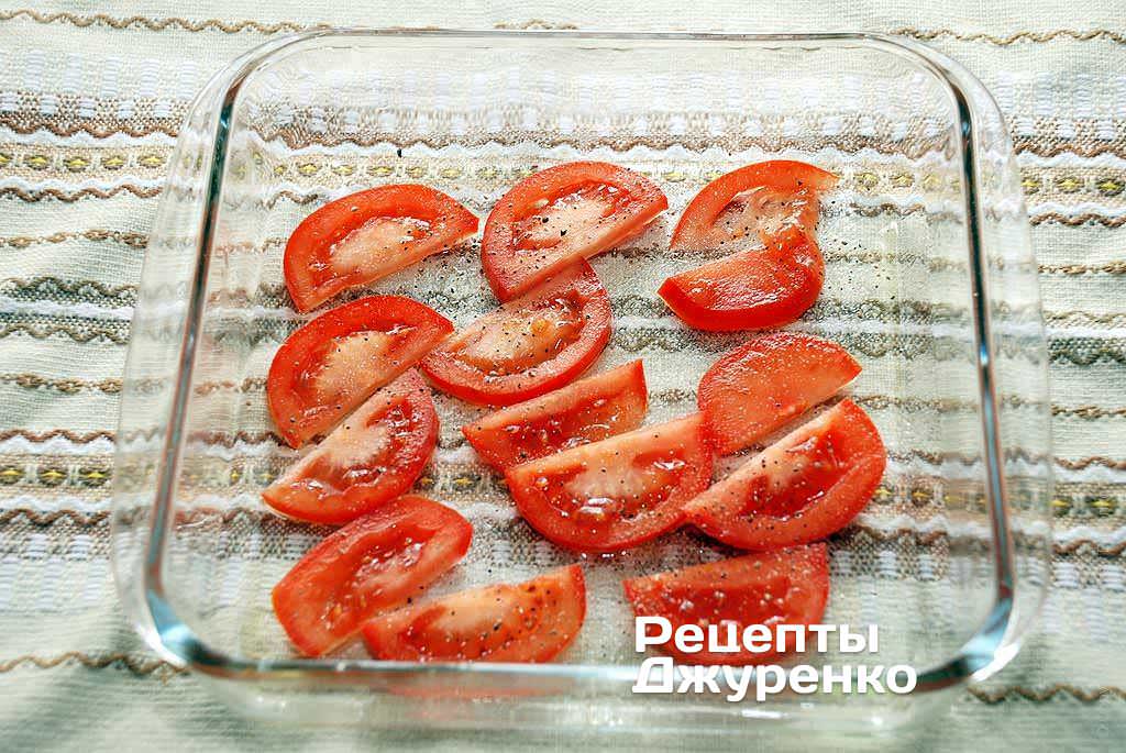 Форму для запікання змастити оливковою олією і розкласти по дну нарізаний тонкими скибочками помідор.