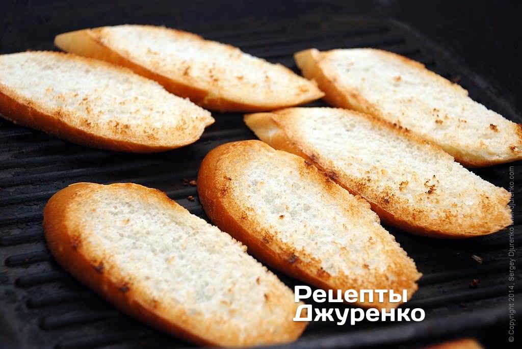 Багет нарезать на ломтики толщиной 12-15 мм сильно наискосок. Поджарить куски хлеба с двух сторон.