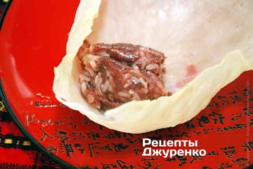Разложите ингредиенты для голубцов на подготовленные капустные листья и заверните голубцы.