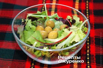 Выложить чистые и сухие листья выбранного салата в миску. Добавить зеленые оливки.