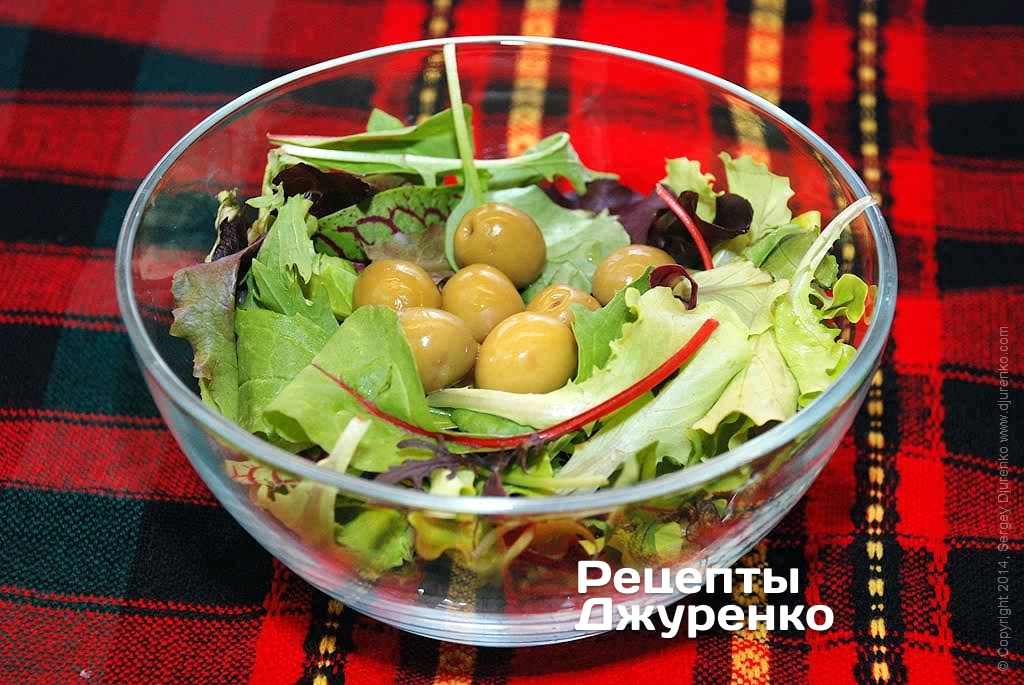 Выложить чистые и сухие листья выбранного салата в миску. Добавить зеленые оливки.