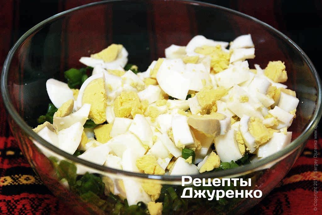 Нарізану для салату зелену цибулю трохи посолити і перемішати, щоб сіль розчинилася. Додати нарізані яйця і перемішати.