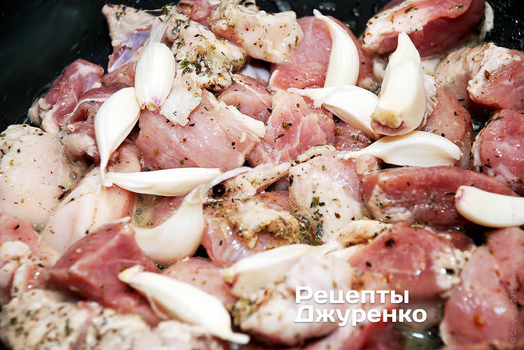 Выложить в сотейник кусочки мяса и зубчики чеснока.