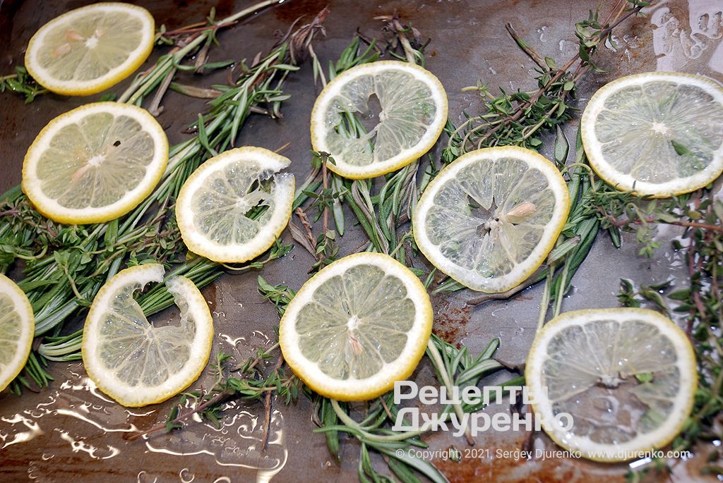 Подготовить противень с подушкой из веточек трав и ломтиков лимона.