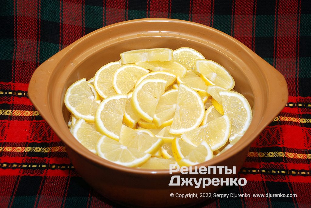 Очищені від шкірки або неочищені лимони нарізати скибочками та скласти в каструлю.