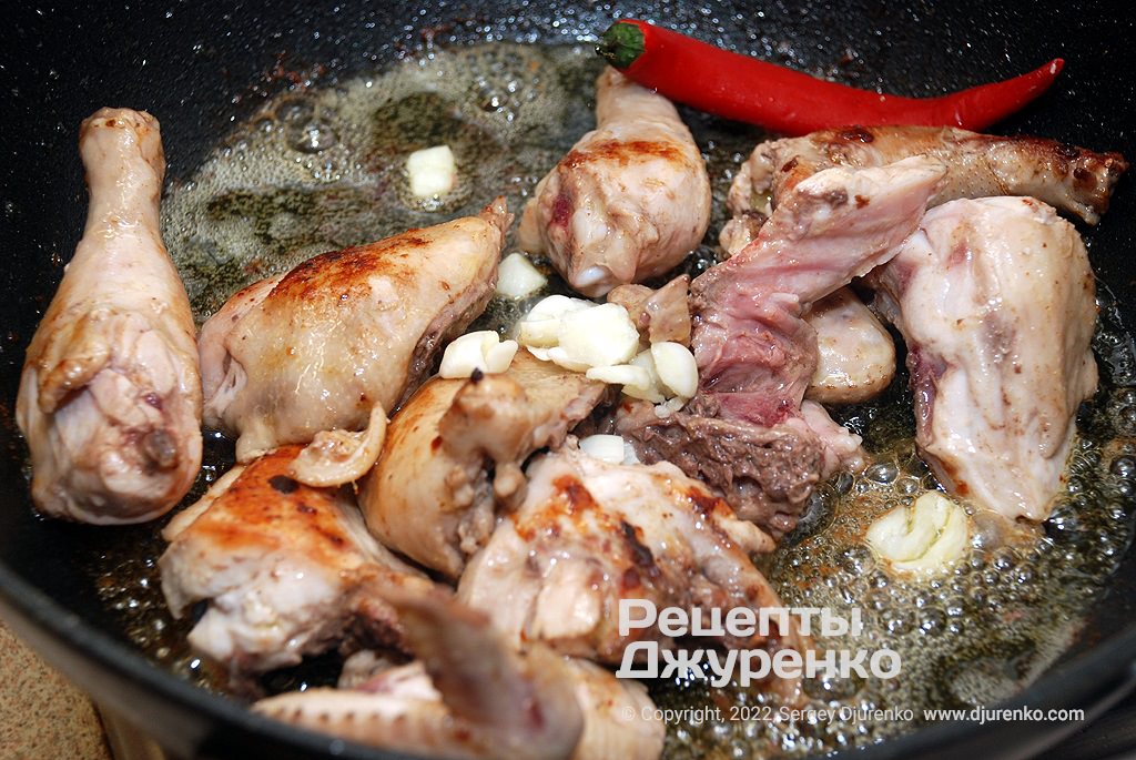 К жареной курице добавить чеснок, специи и острый перец.
