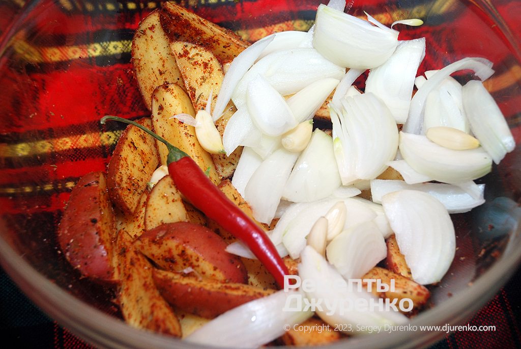 Часточки картоплі змішати зі спеціями, додати олію та овочі.