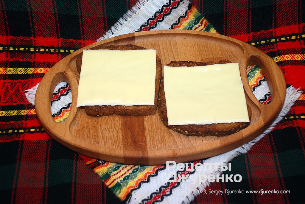 Положить хлеб на тарелку и добавить по кусочку плавленого сыра.